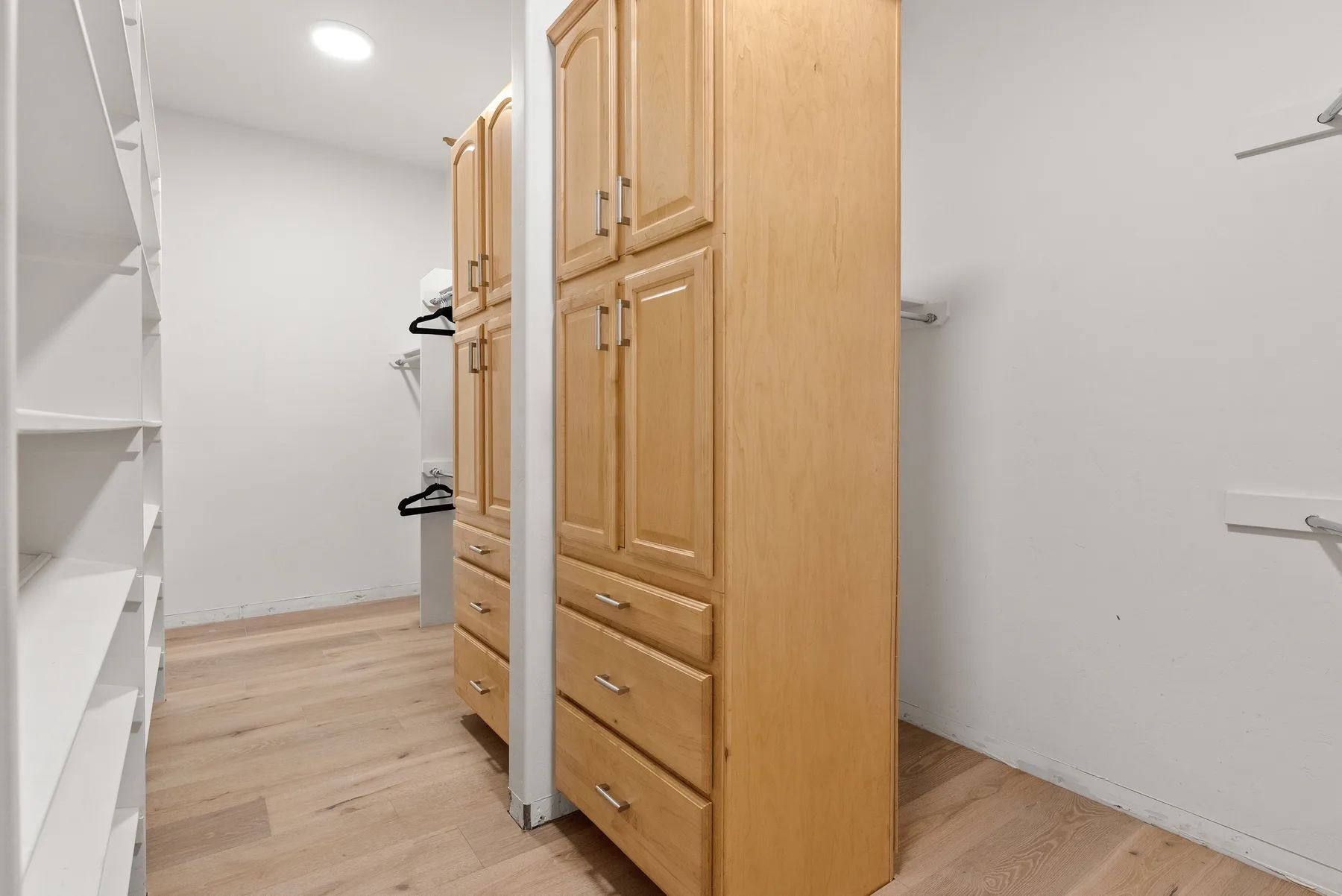 Un vestidor con armarios de madera, cajones y estantes abiertos.