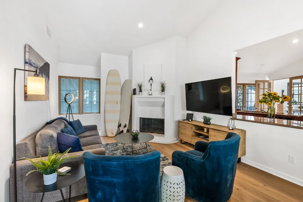 Una sala de estar con chimenea, televisor y asientos azules.