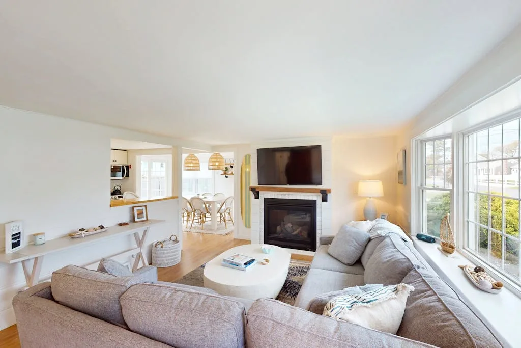 A bright living room with seating, a fireplace, and large windows.