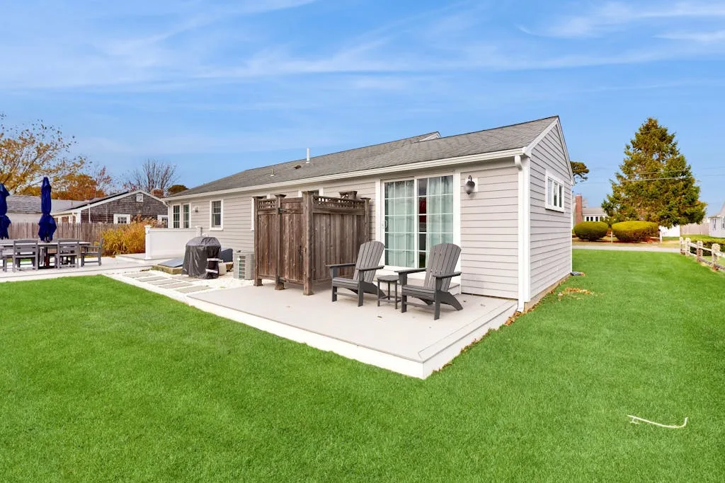 A light-sided outbuilding opens onto a paved patio with outdoor seating.
