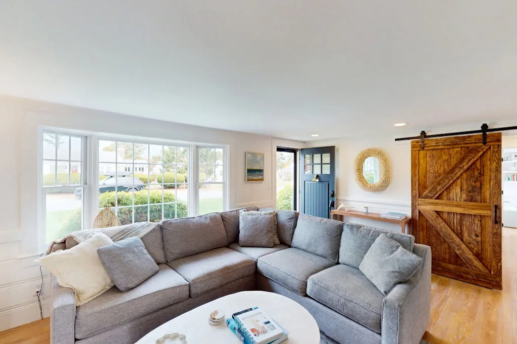 A living room with a gray sectional and large windows.