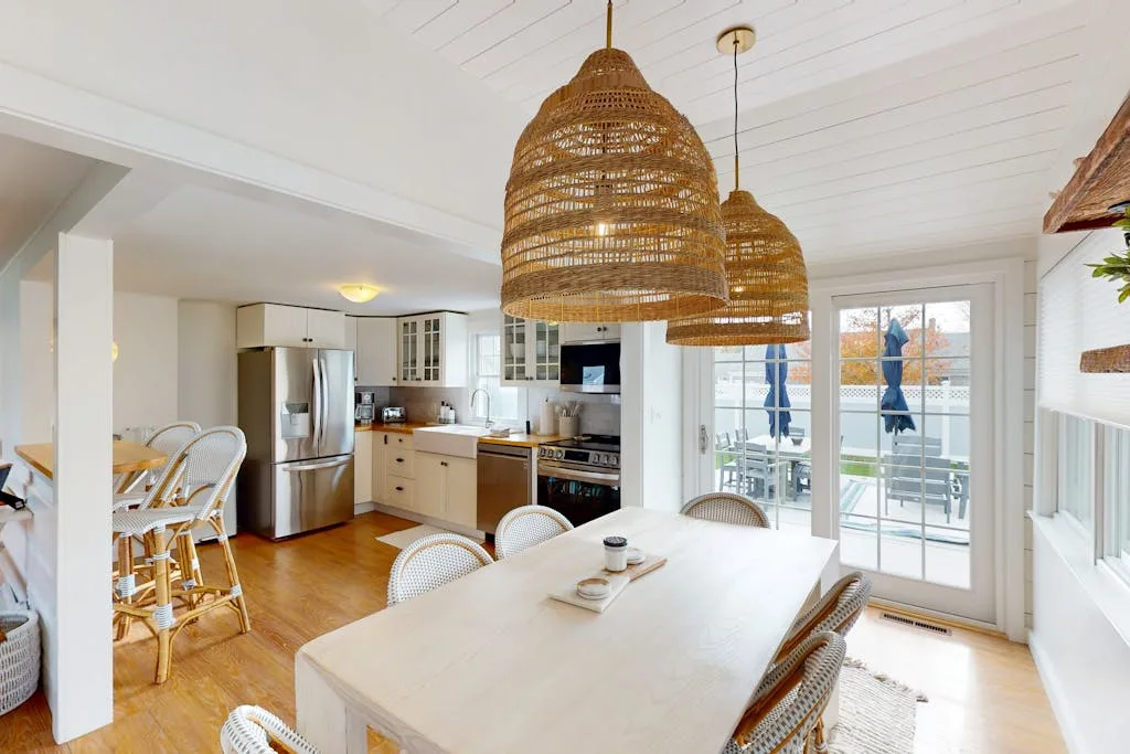 A bright open-plan kitchen and dining area with a table beside glass doors.