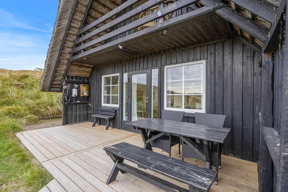 A wooden deck with a picnic table sits beside a dark-sided cabin.