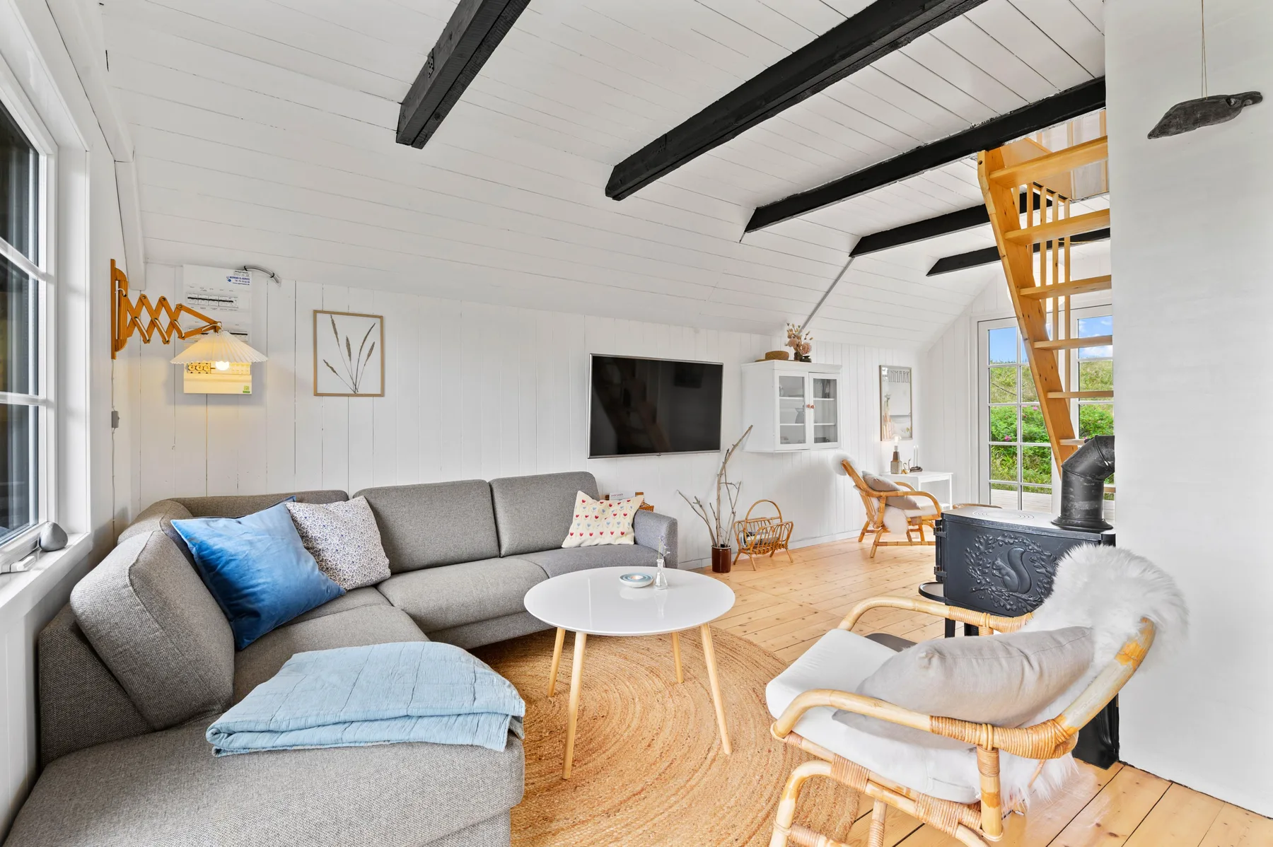 A bright living room with seating, a television, and a wood-burning stove.