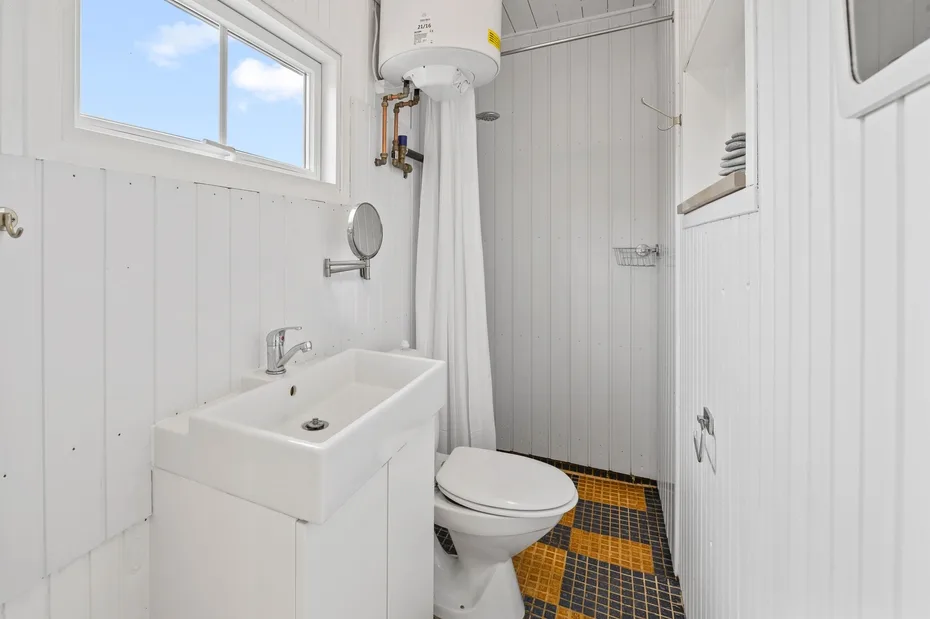 A compact bathroom with a sink, toilet, and tiled floor.