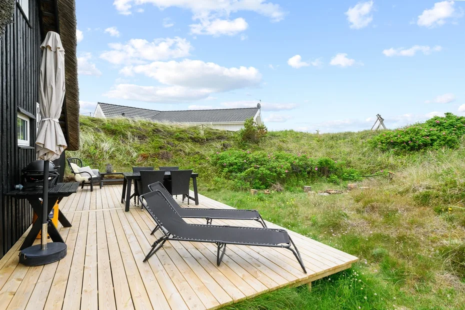 A wooden deck with outdoor seating overlooks a grassy landscape.