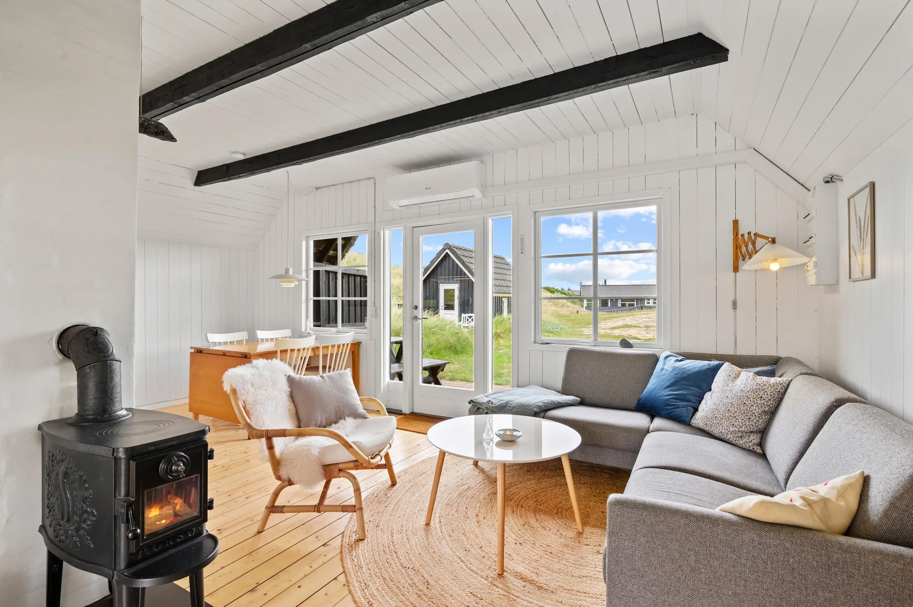 A bright living room with a sectional seating area and a wood-burning stove.