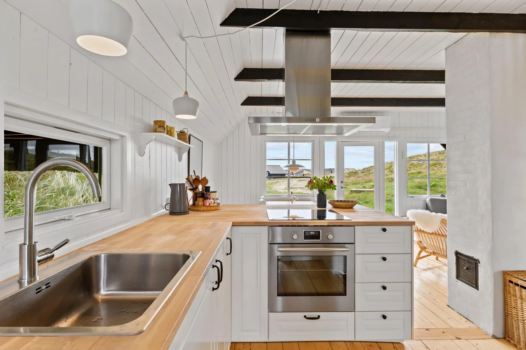 A bright kitchen with a central cooking island and large windows overlooking green hills.