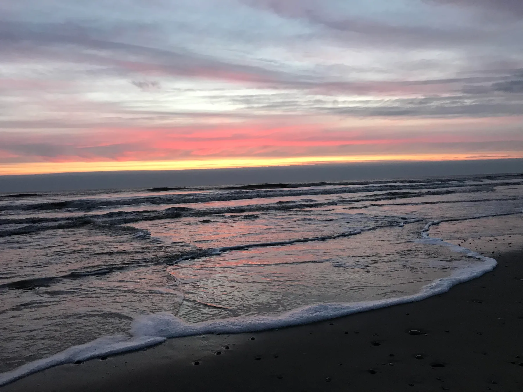 A beach at sunset, with gentle waves washing onto the shore.