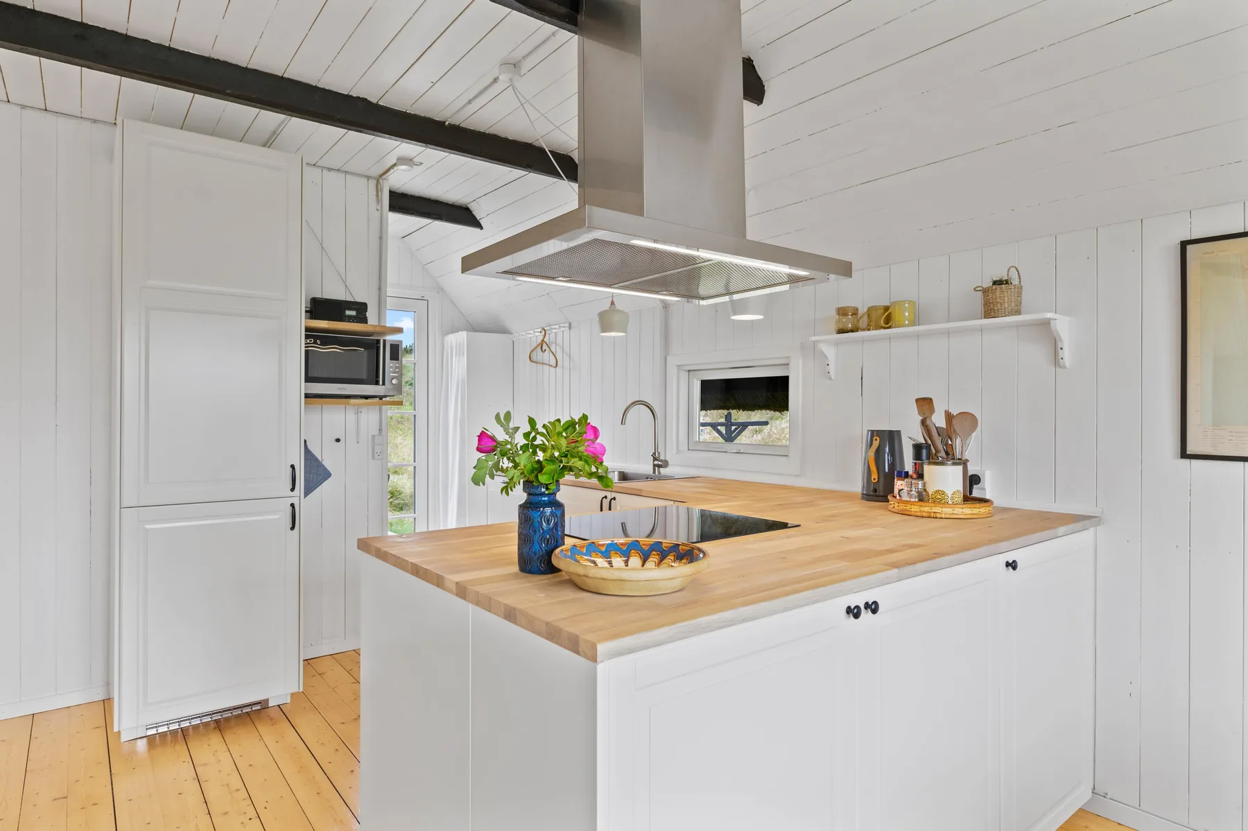 A bright kitchen with a wooden countertop and white cabinets.