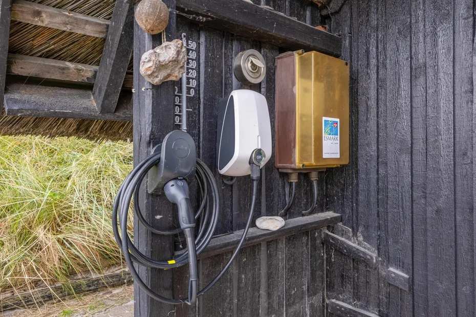 A charging station is mounted on a dark wooden wall beside a grassy area.