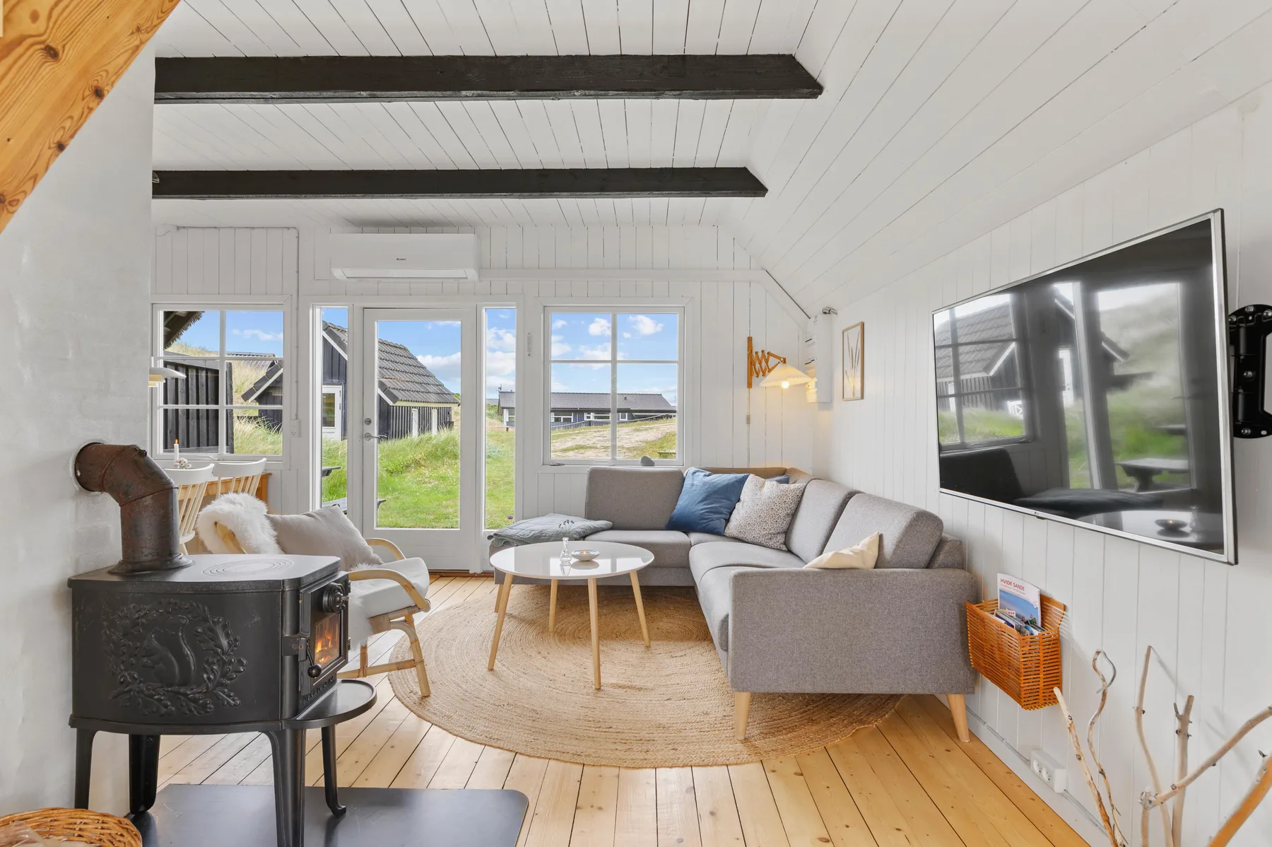 A bright living room with seating arranged around a coffee table and a wood stove.