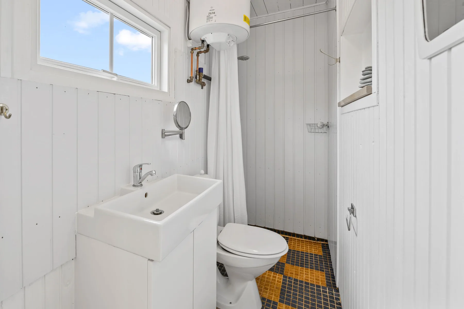 A compact bathroom with a white sink, toilet, and shower.