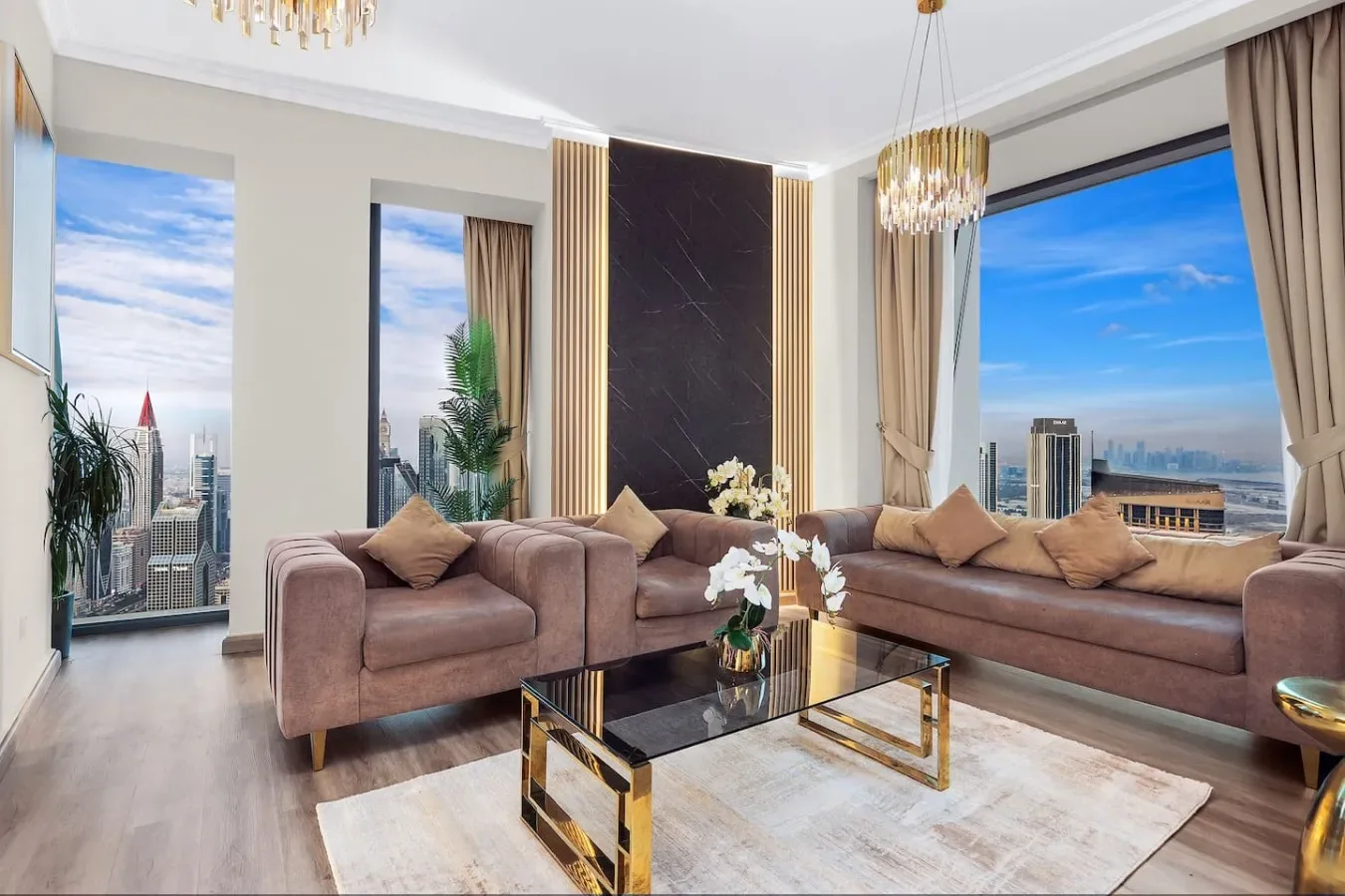 A bright living room has seating beside large windows overlooking the city.