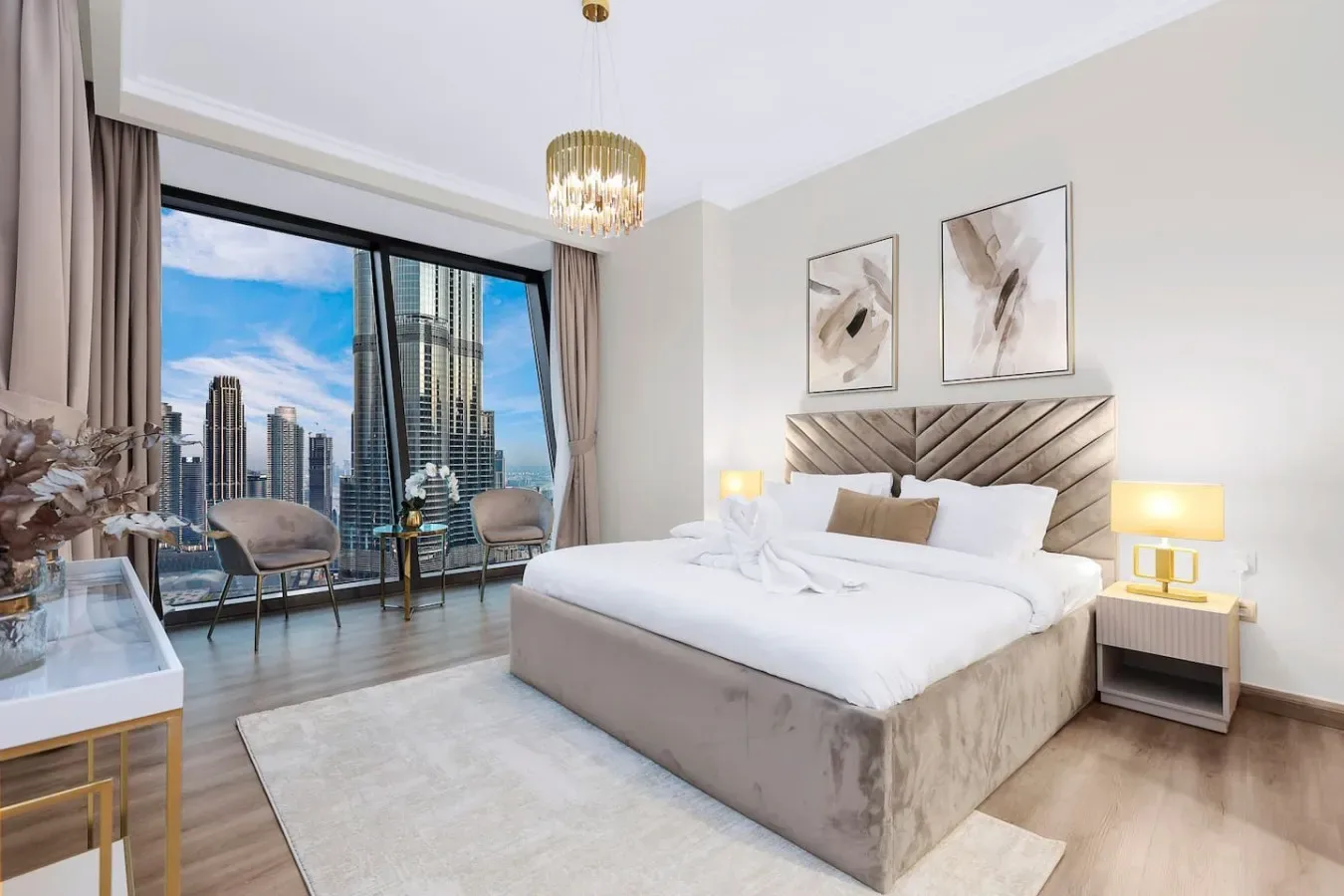 Un dormitorio luminoso con una cama grande y ventanales con vistas a edificios de la ciudad.