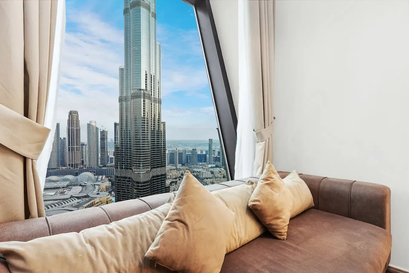 A seating area by a large window overlooks a city skyline.