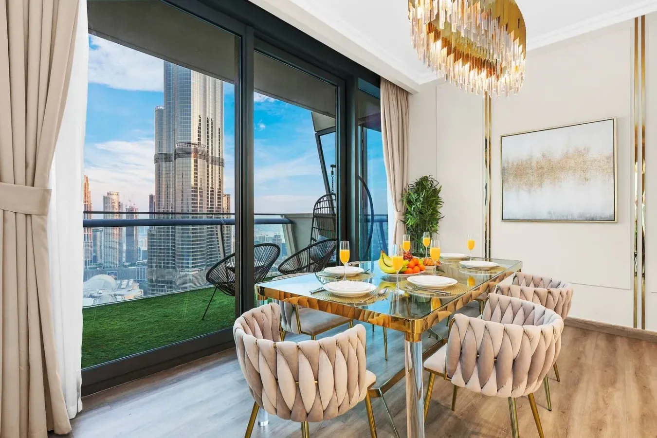 Comedor con mesa de vidrio y asientos tapizados junto a ventanales de piso a techo.