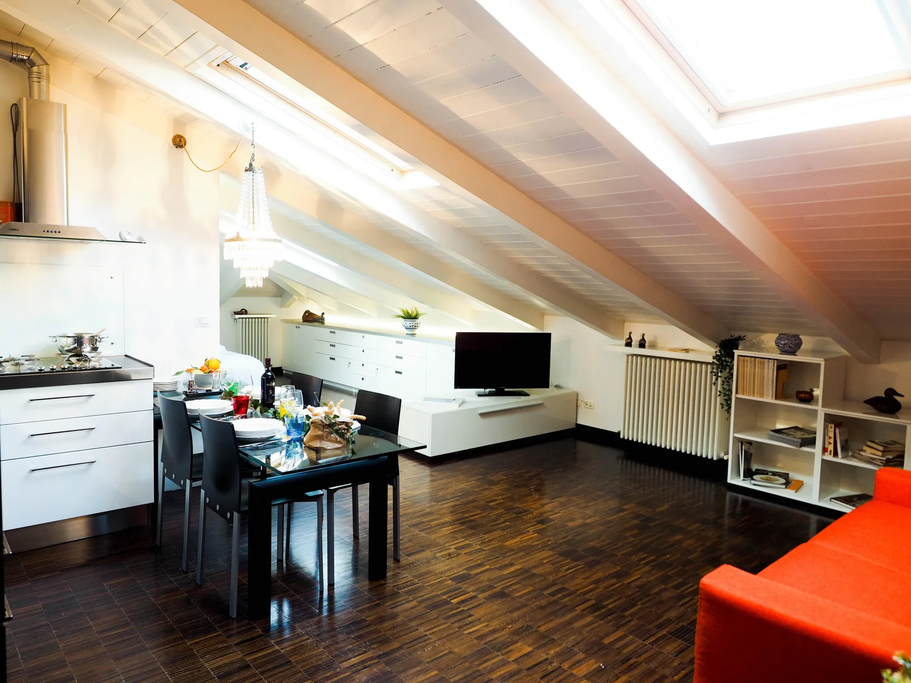 Una luminosa sala de estar y comedor en el ático, con mesa, asientos y televisor.
