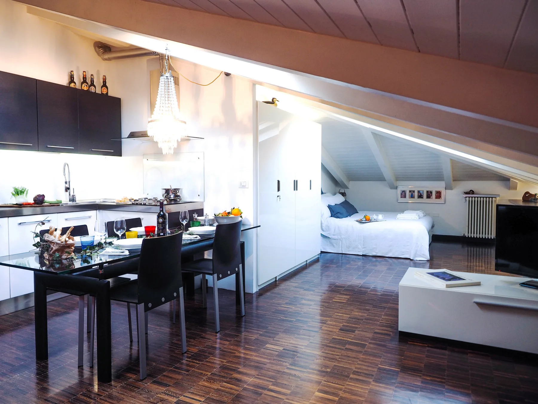Una estancia abuhardillada diáfana combina una zona de comedor y cocina con una cama bajo el techo inclinado.