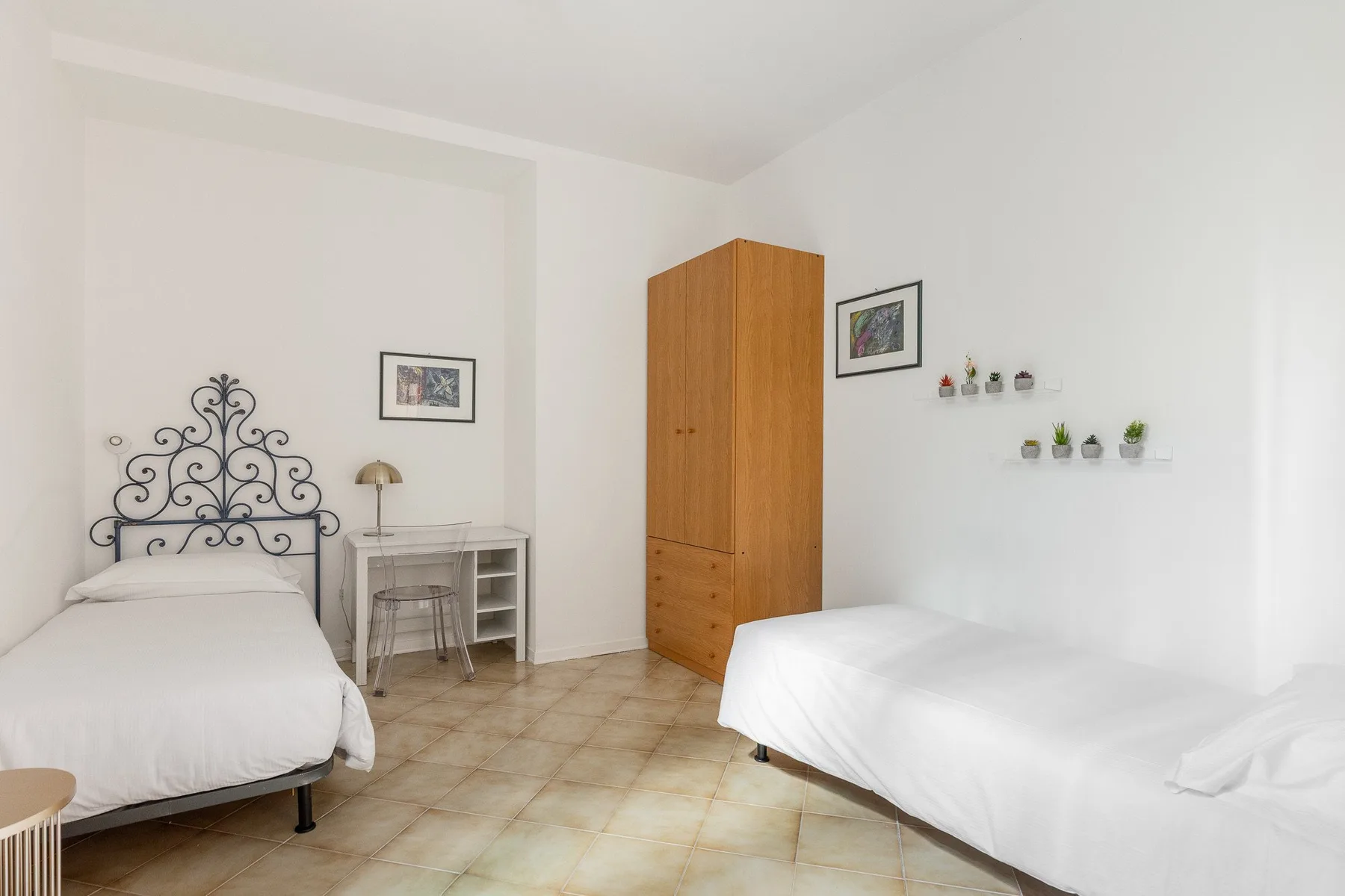 A bright bedroom with two beds and a wooden wardrobe.