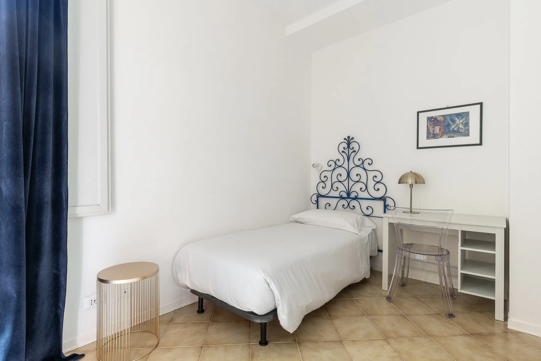 Un dormitorio con una cama bien tendida y un escritorio junto a la pared.
