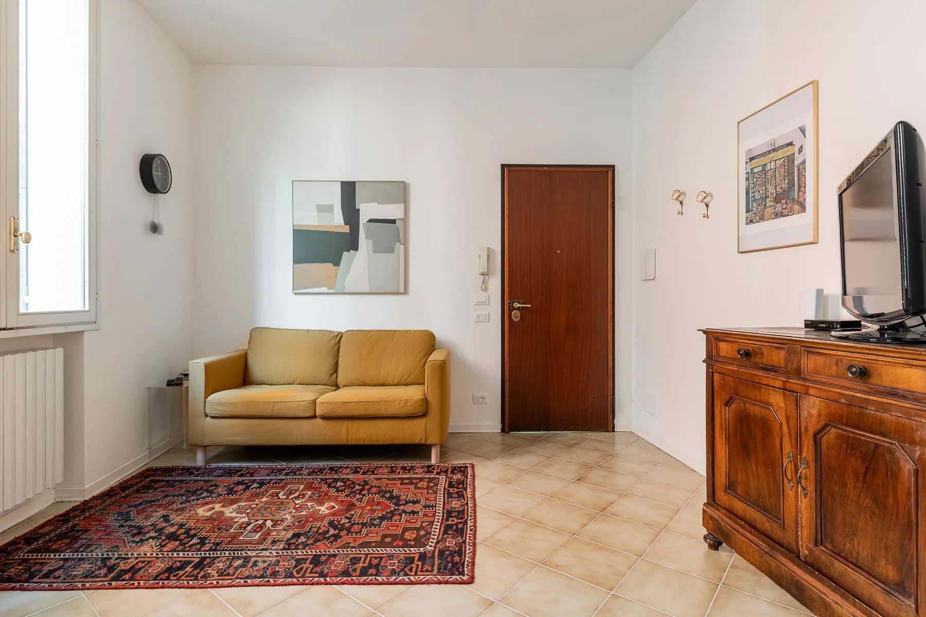 A living room with a sofa, patterned rug, and wooden cabinet.