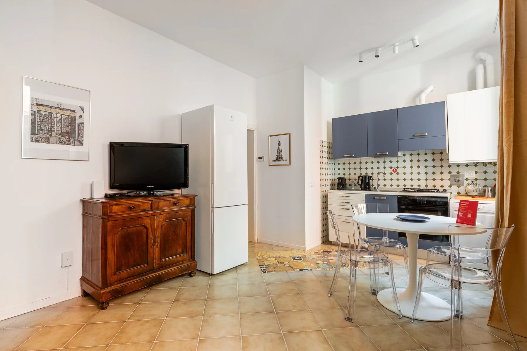Una cocina y comedor luminosos con gabinetes azules y una mesa redonda.