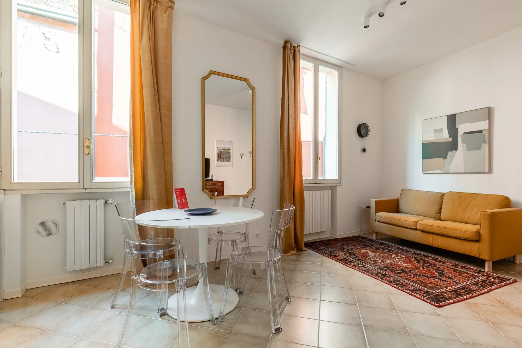A bright living room with a dining table, seating, and tall windows.