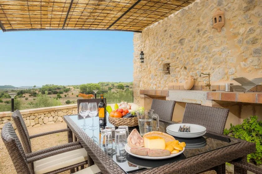 Comedor al aire libre bajo un toldo sombreado, con una mesa preparada para comer.