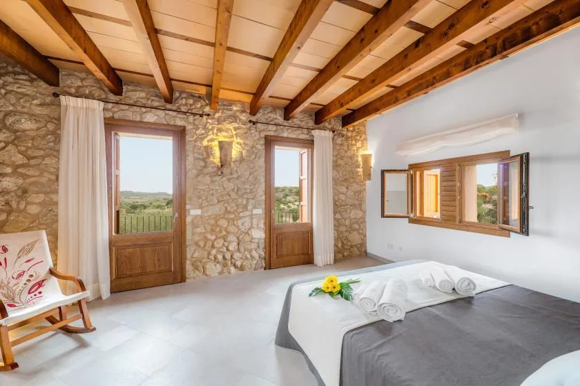 Un dormitorio con una cama, vigas de madera a la vista y paredes de piedra.
