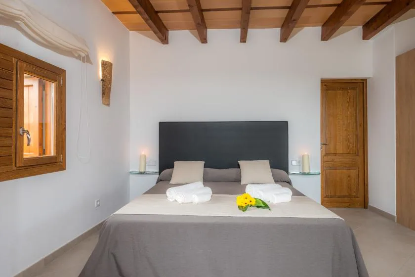 Un dormitorio con una cama grande, almohadas y vigas de madera a la vista.