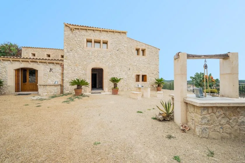 Una casa de piedra da a un patio de tierra con plantas en macetas.