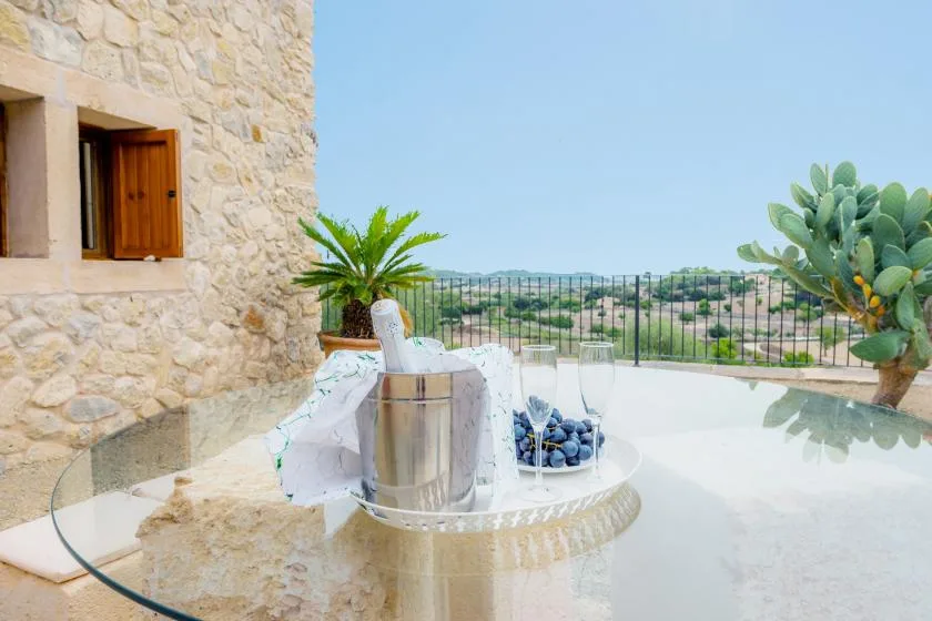 A stone terrace with a small round table overlooks a distant landscape.