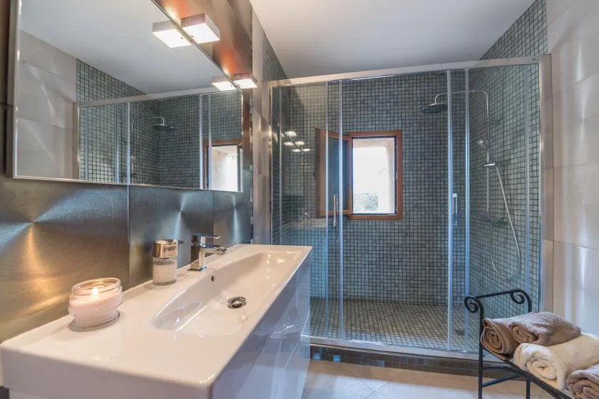 Un baño con una encimera de lavabo larga y una ducha acristalada.