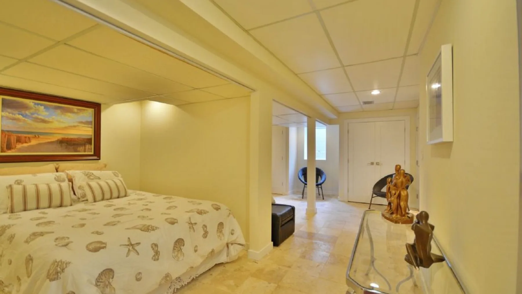 A bedroom with patterned bedding and a hallway leading to a closed door.