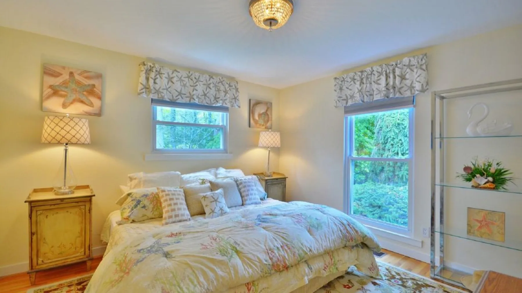 A bedroom with a large bed between two windows.