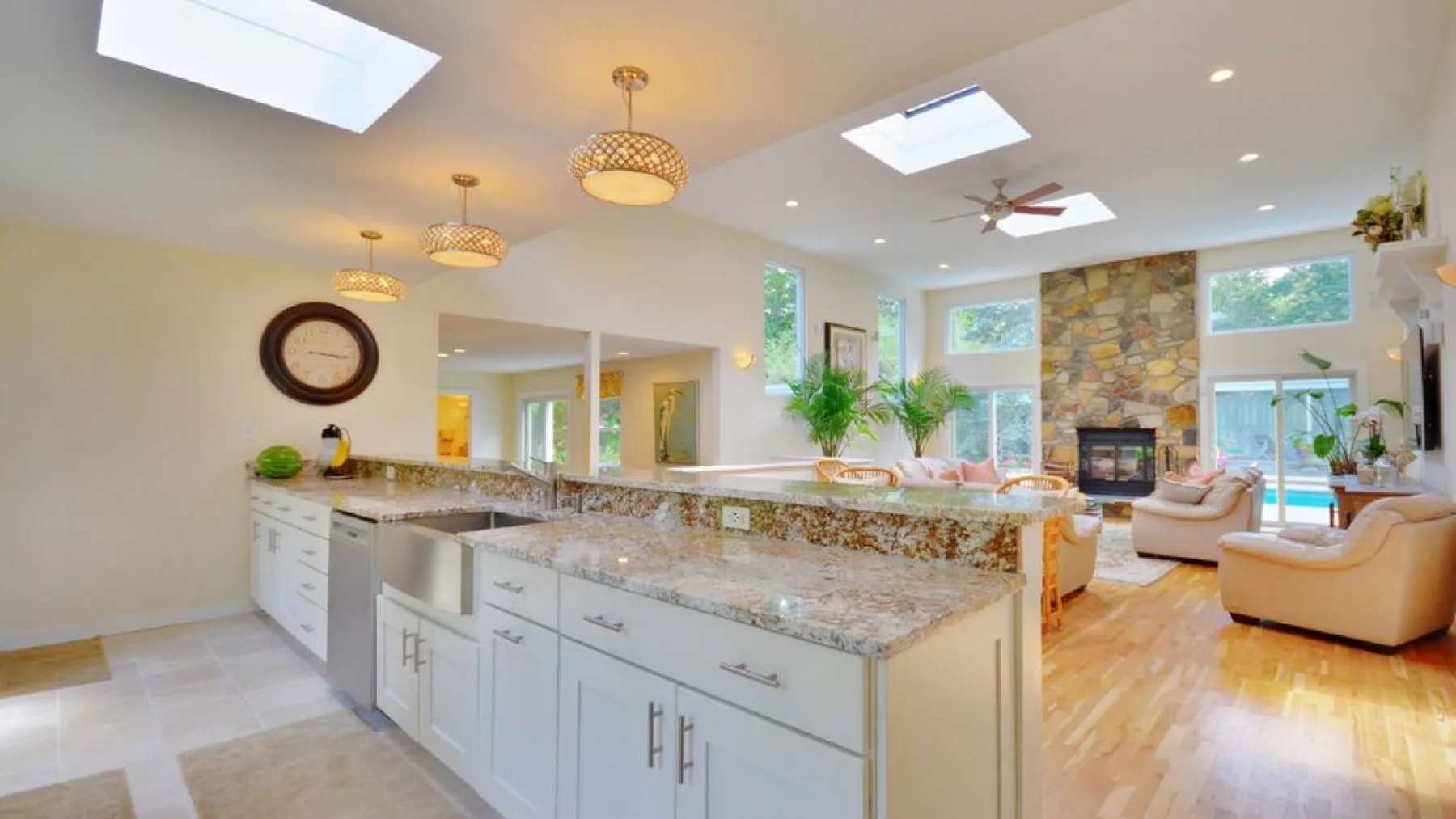 An open-plan kitchen and living area with a stone island and fireplace.