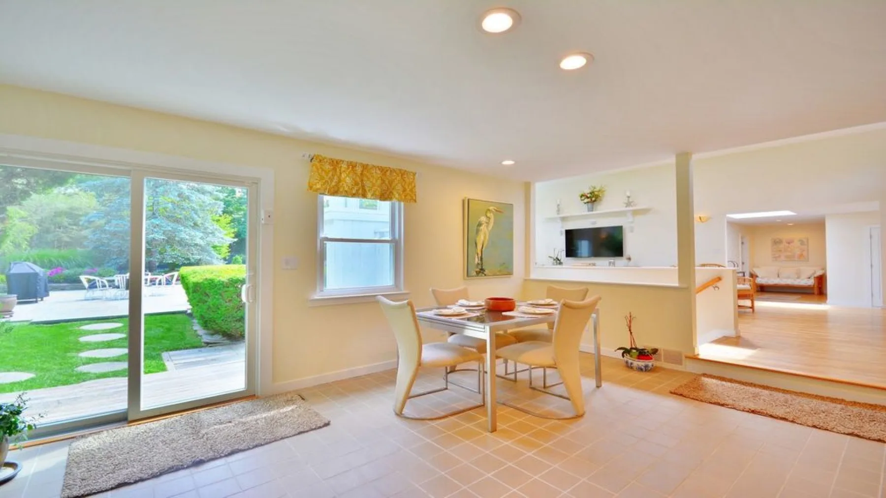 A bright dining area with a table and sliding glass doors opening onto a garden.