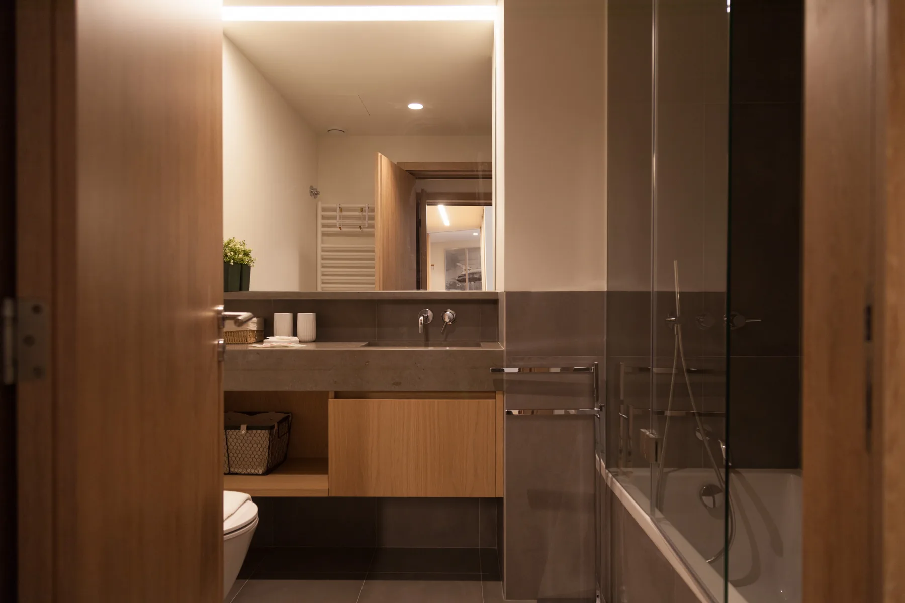 Un baño con lavabo y bañera detrás de una mampara de vidrio.