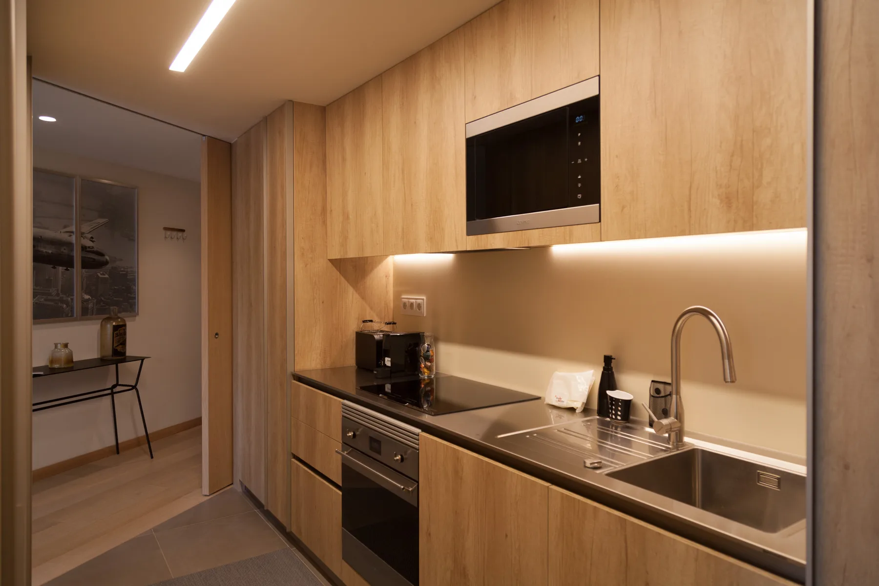 Una cocina compacta con gabinetes de madera, una placa de cocina y un fregadero.