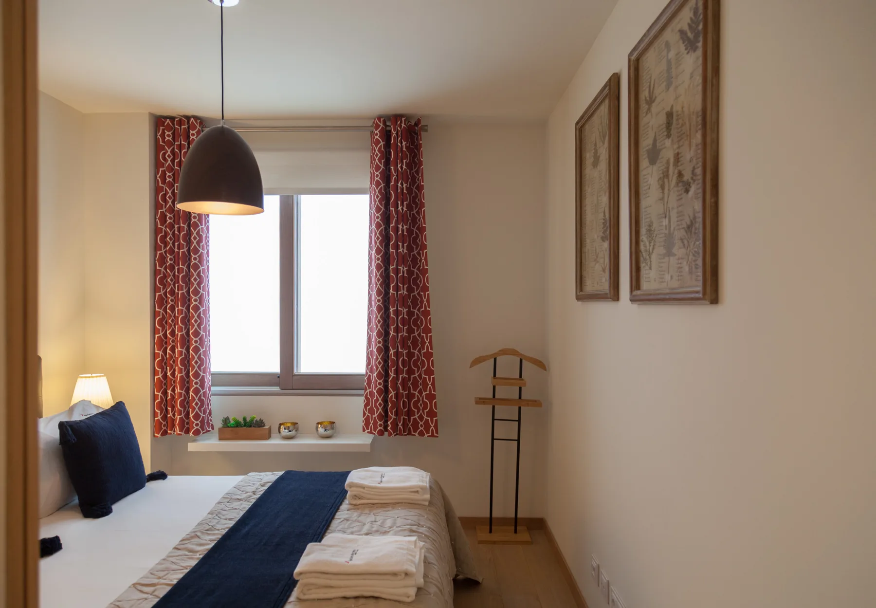 Un dormitorio con una cama, cortinas rojas y una ventana.