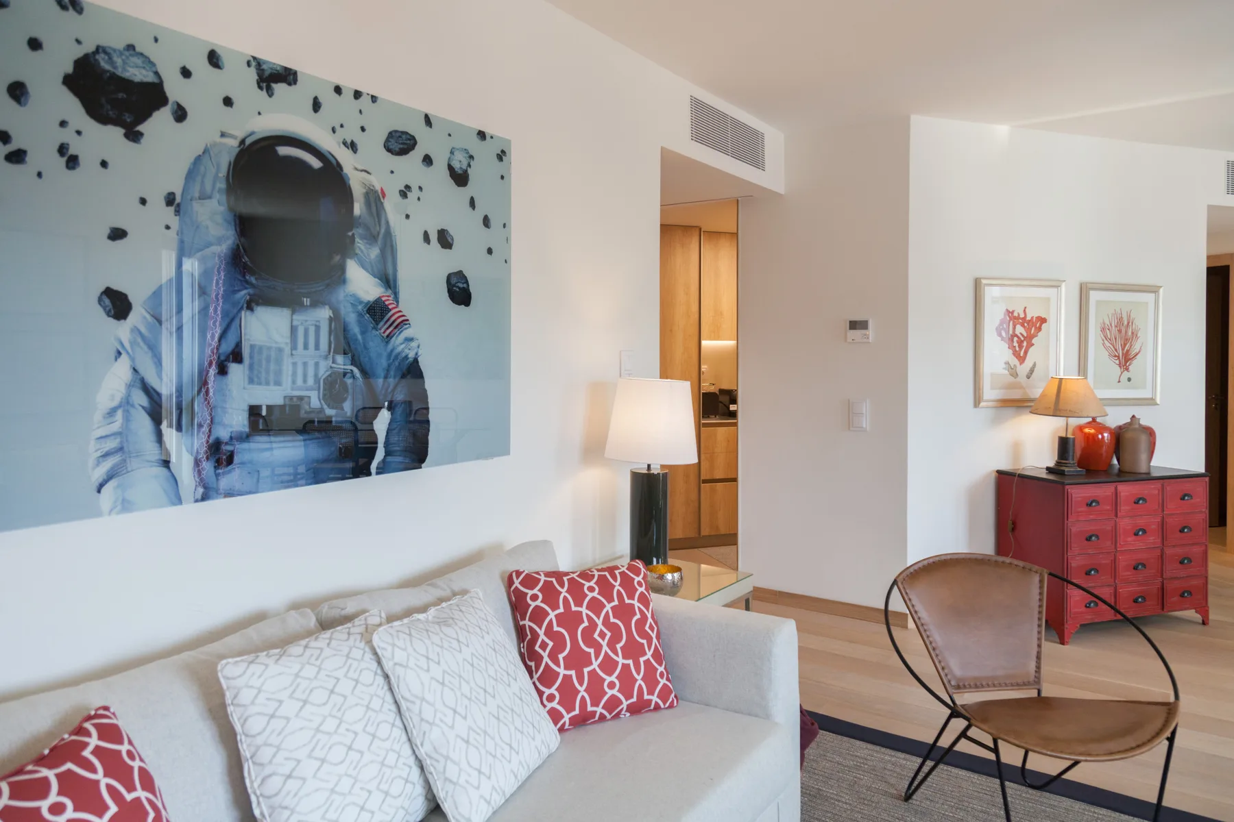 Sala de estar con un sofá, cuadros enmarcados y una cómoda roja.