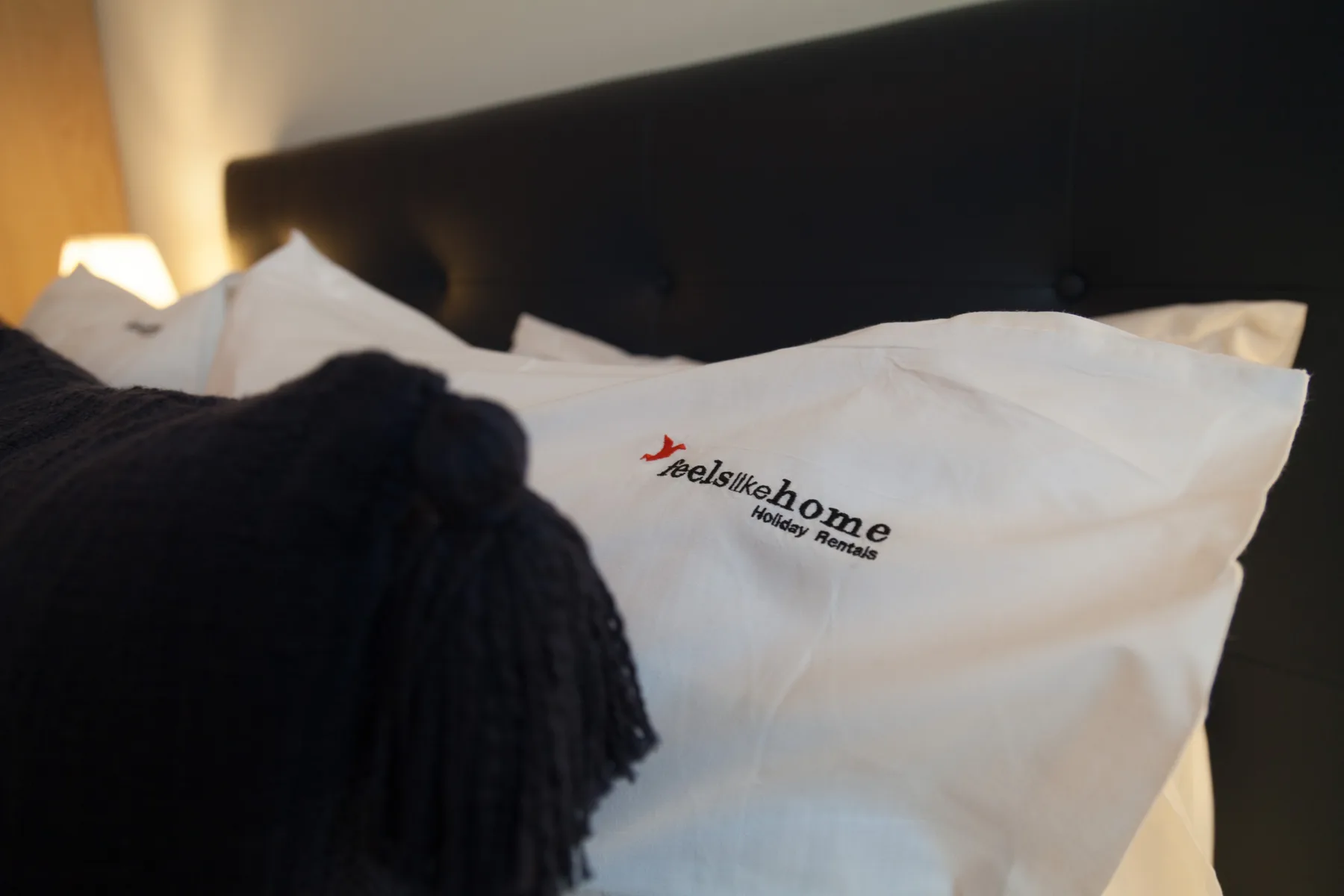 Un dormitorio con almohadas blancas junto a un cabecero tapizado oscuro.