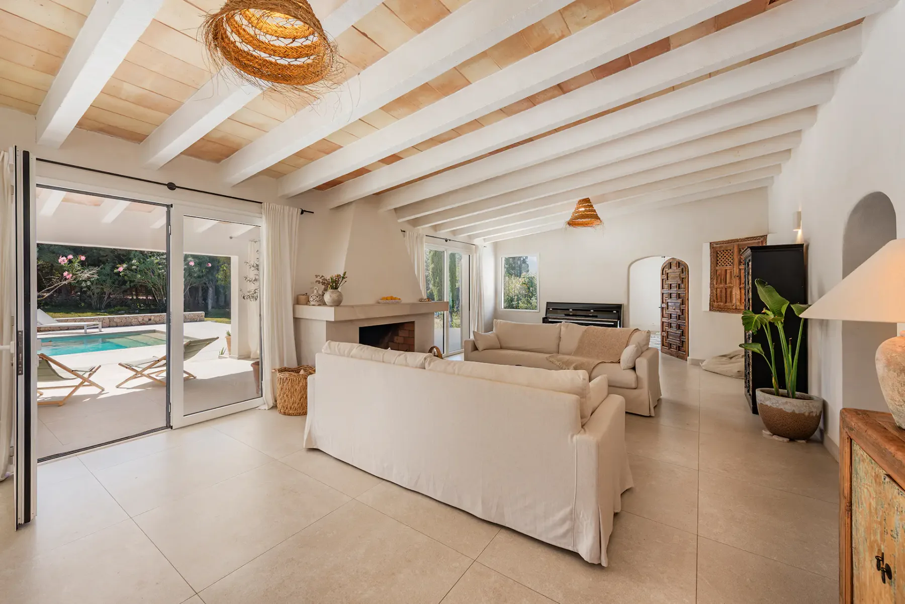 A bright living room with neutral seating, a fireplace, and sliding glass doors opening to a patio.