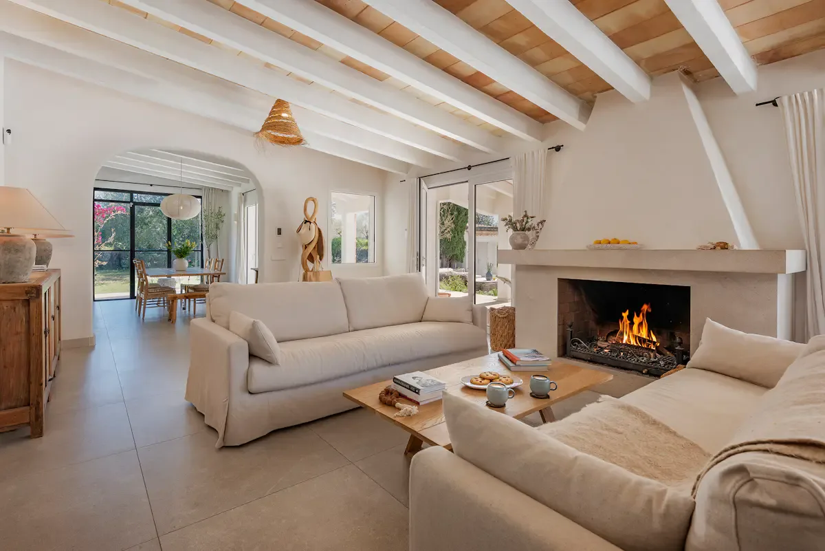 A bright living room with seating arranged around a coffee table and fireplace.