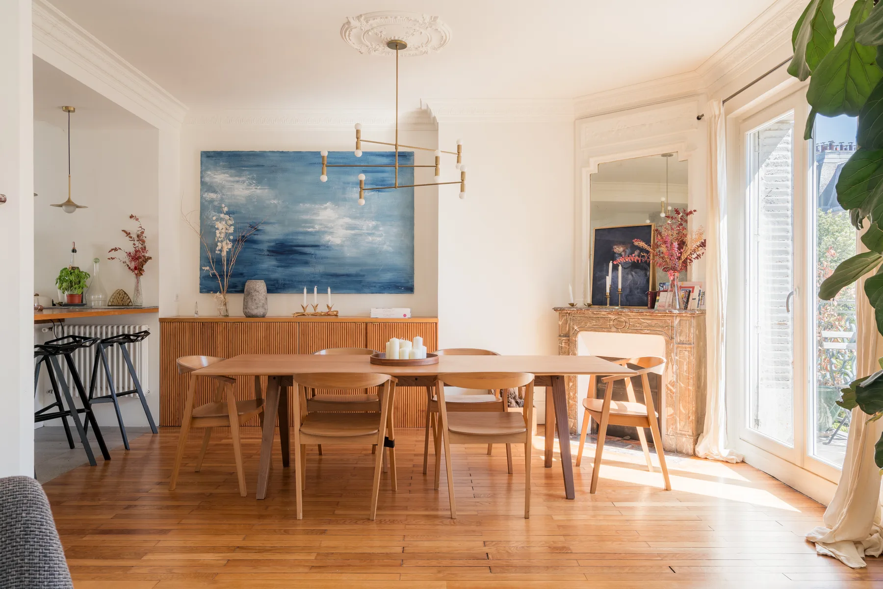 A bright dining area with a long wooden table beside large windows.