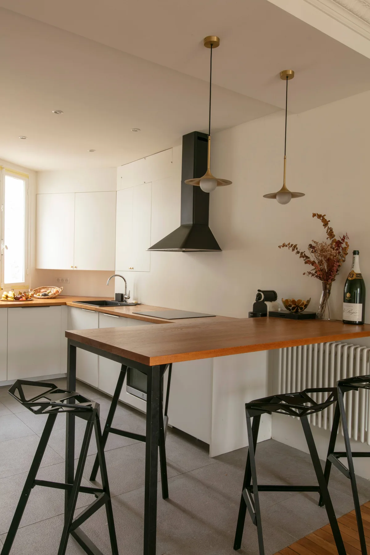 A modern kitchen with a central island and pendant lights.