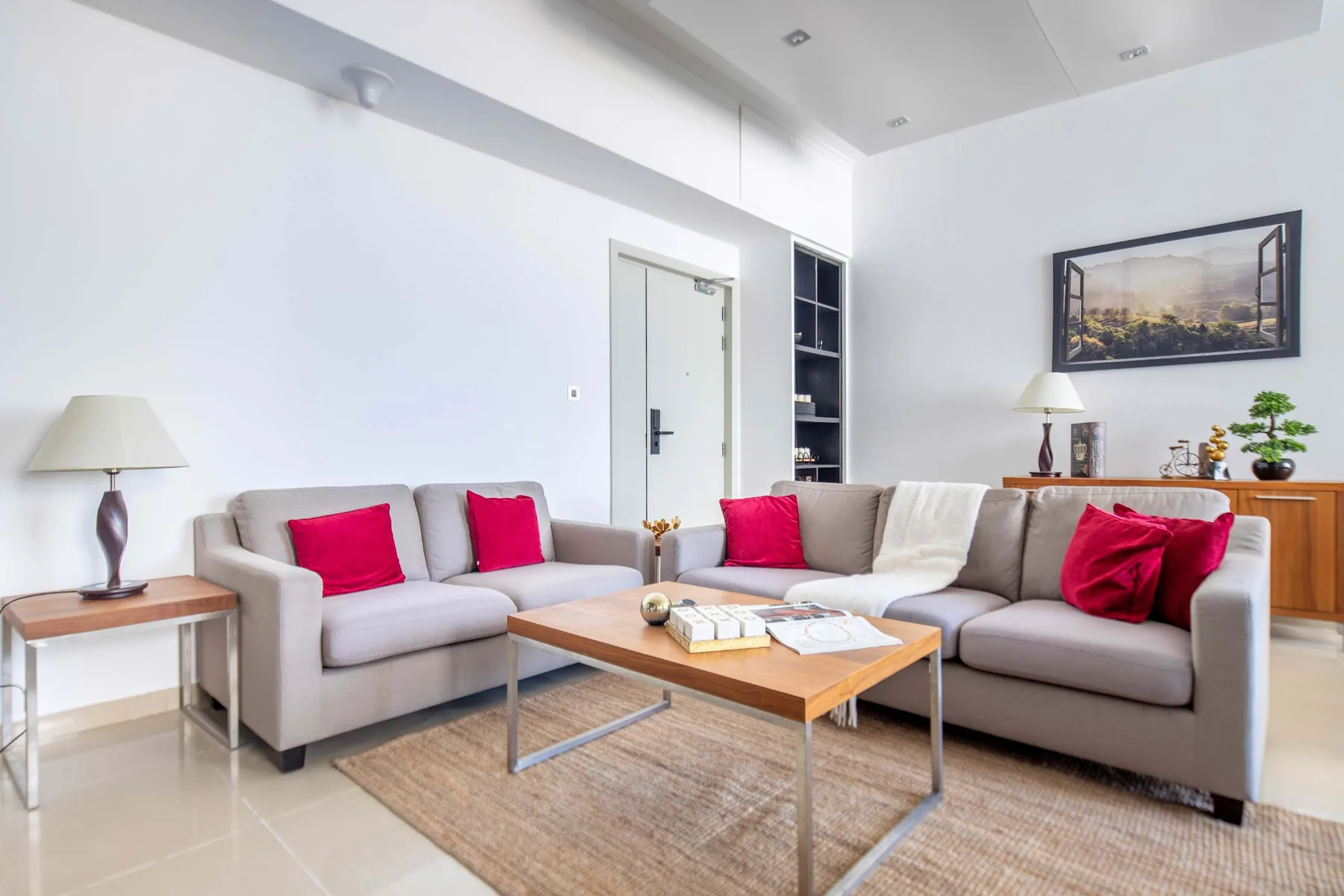 Una sala luminosa con asientos grises, cojines de colores y una mesa de centro de madera.