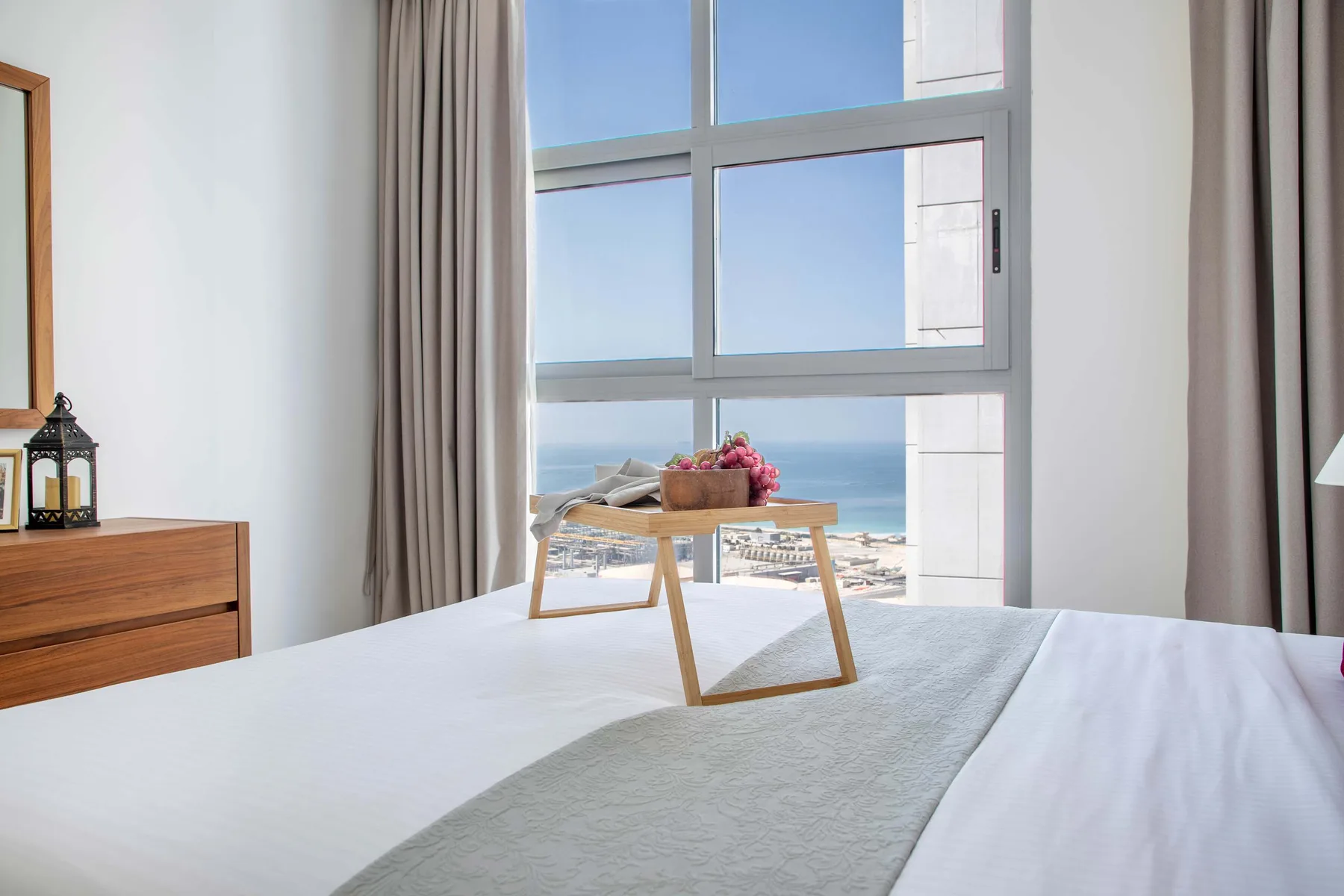 A bright bedroom with a large window overlooking the sea.