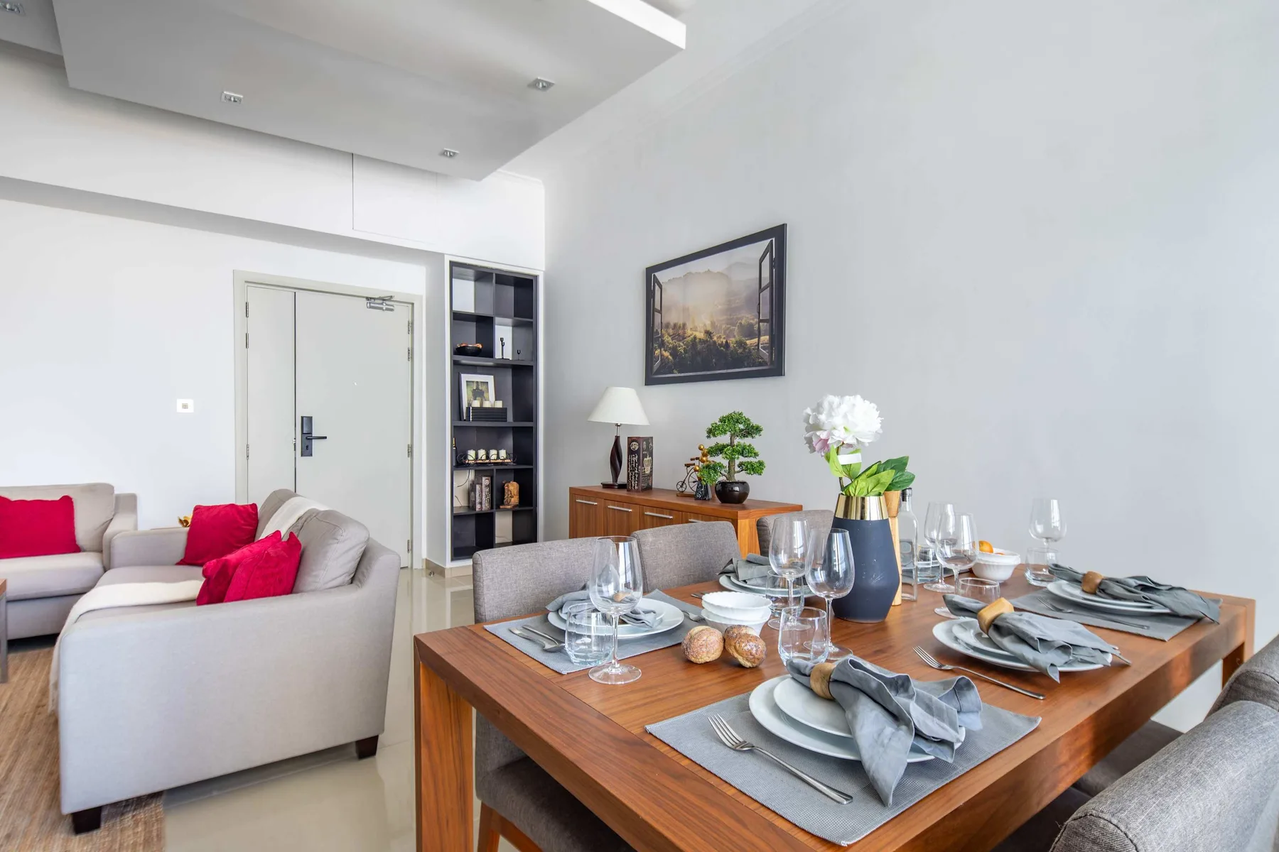 A dining area with a set table beside a living room seating area.
